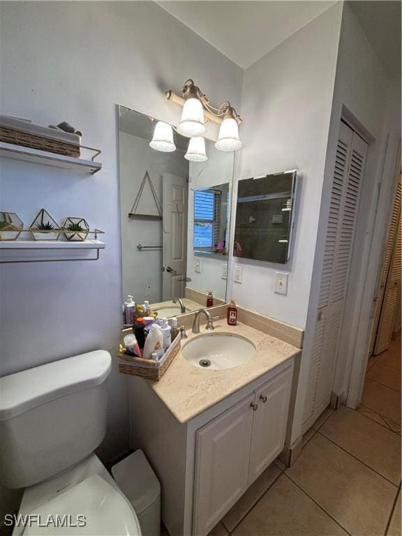 bathroom featuring toilet, vanity, a closet, and tile patterned floors