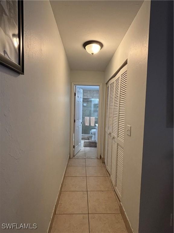 corridor featuring light tile patterned flooring and baseboards