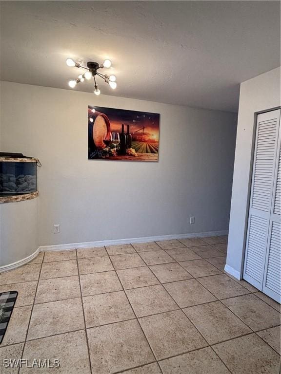 tiled spare room featuring baseboards