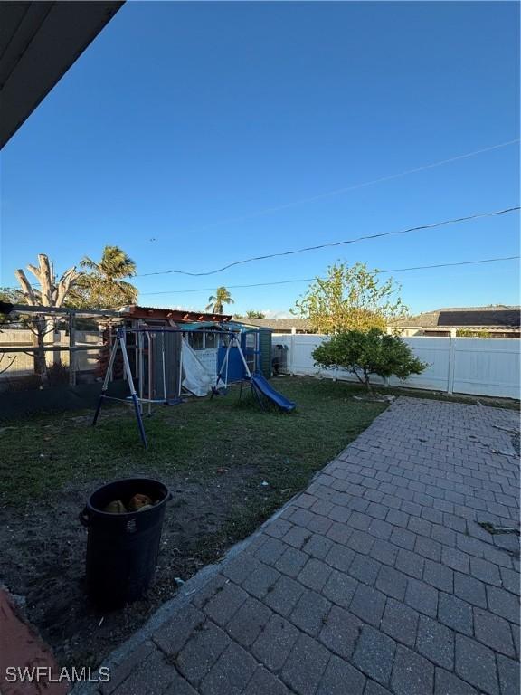 view of yard with a patio area, a playground, and a fenced backyard