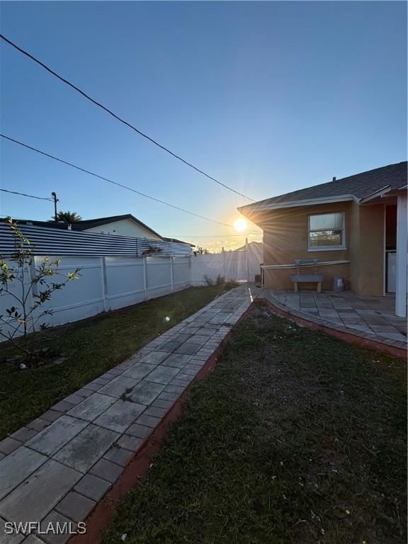 yard at dusk with a patio area and a fenced backyard