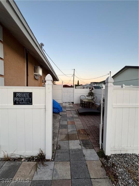 exterior space with a wall mounted air conditioner and fence