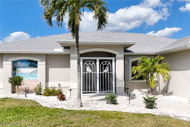 doorway to property featuring roof with shingles and stucco siding