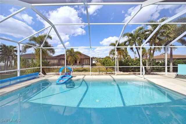 view of pool with glass enclosure, a patio area, and a covered pool