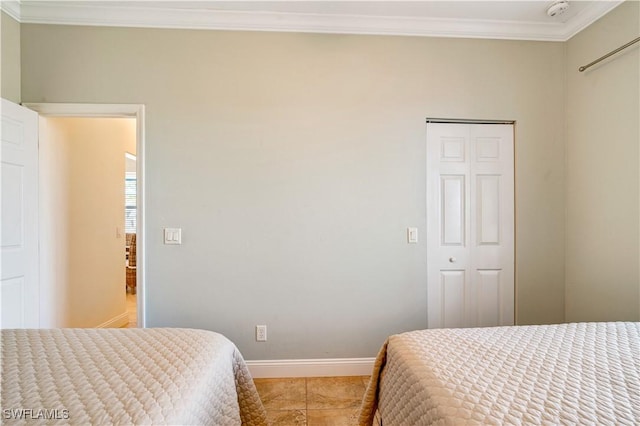 bedroom featuring a closet, baseboards, and crown molding