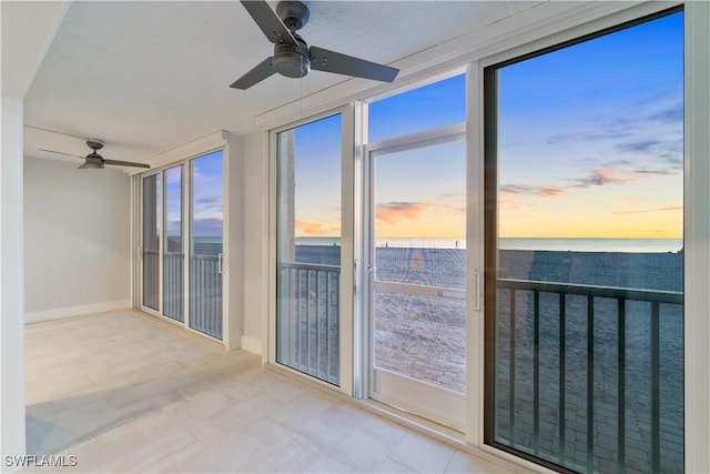 unfurnished sunroom with ceiling fan and a water view