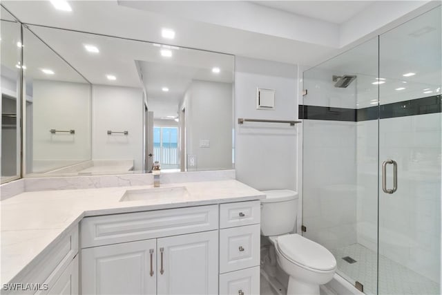 bathroom featuring toilet, a stall shower, recessed lighting, and vanity