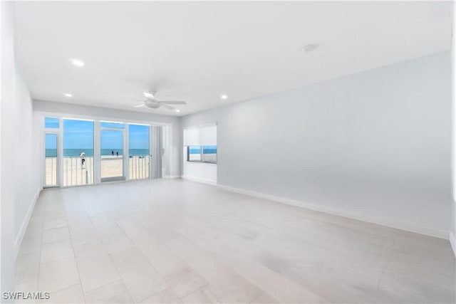 unfurnished room with recessed lighting, a water view, a ceiling fan, and baseboards