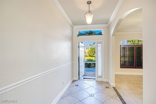 tiled entryway with ornamental molding, arched walkways, a textured wall, and baseboards