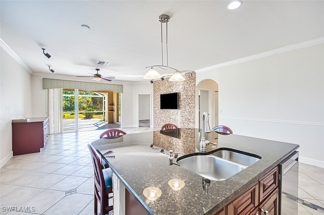 kitchen featuring a center island with sink, arched walkways, ornamental molding, open floor plan, and a sink