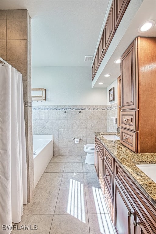 bathroom with a garden tub, a sink, visible vents, tile walls, and tile patterned floors