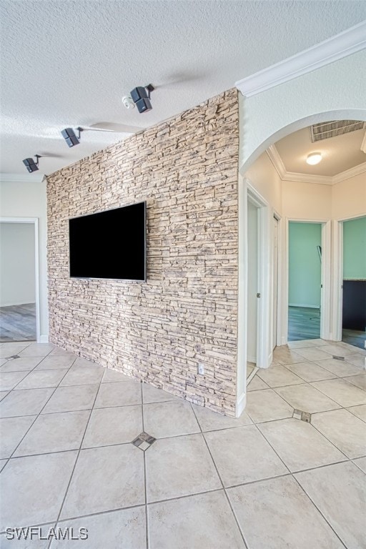 unfurnished living room featuring arched walkways, ornamental molding, visible vents, and tile patterned floors