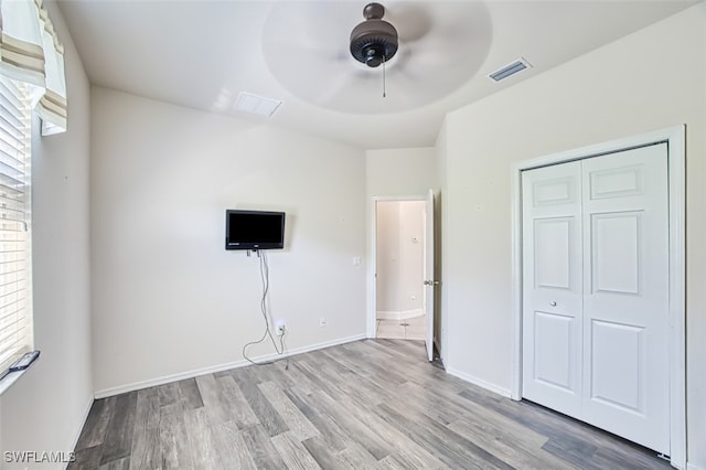 unfurnished bedroom featuring multiple windows, wood finished floors, visible vents, and baseboards