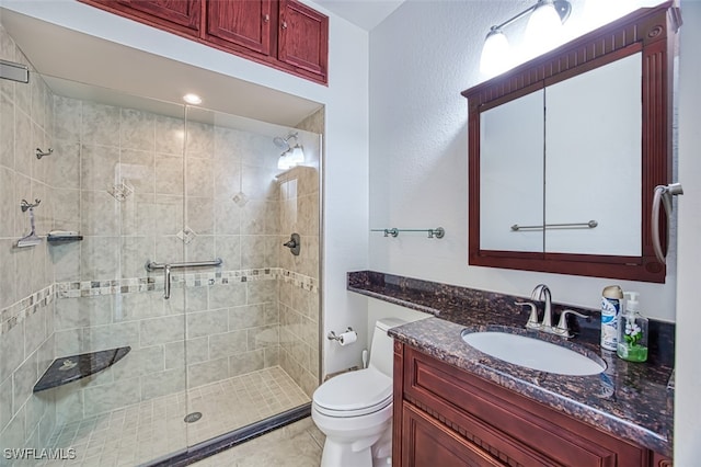 bathroom with tile patterned floors, a shower stall, toilet, and vanity