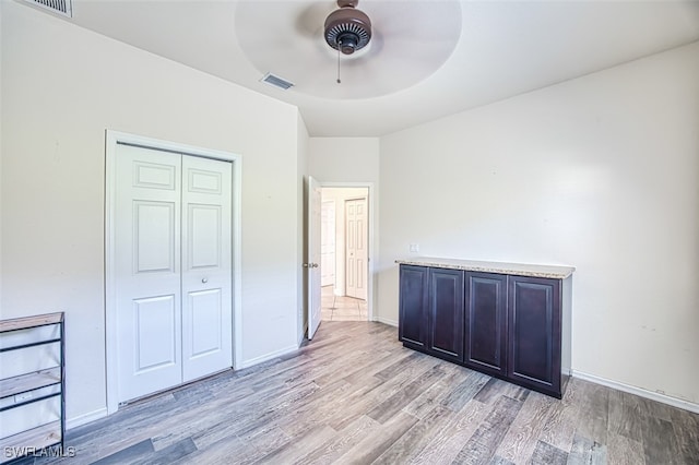 unfurnished bedroom featuring light wood finished floors, baseboards, visible vents, and a closet