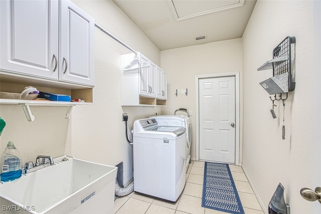 laundry room featuring light tile patterned floors, cabinet space, visible vents, a sink, and separate washer and dryer