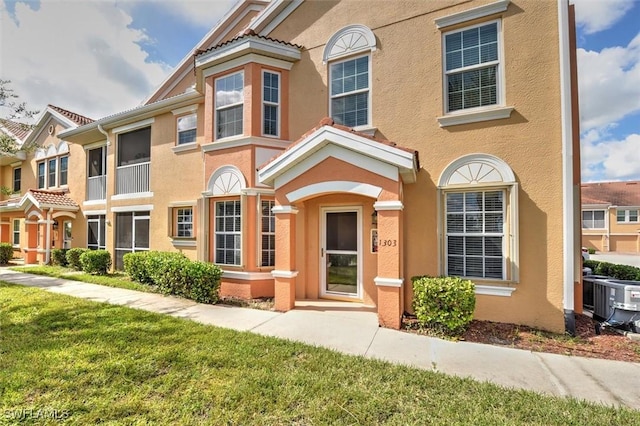 view of property with a front lawn, cooling unit, and stucco siding