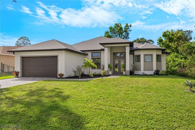 prairie-style house with an attached garage, decorative driveway, french doors, a front lawn, and stucco siding