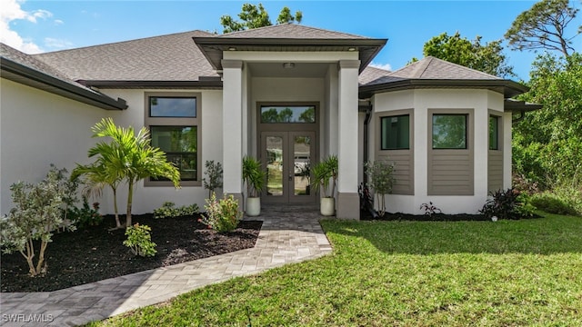 entrance to property featuring roof with shingles, french doors, a lawn, and stucco siding