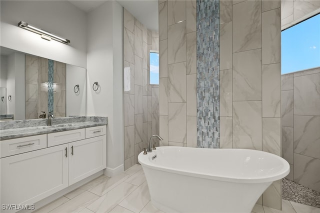 bathroom with a healthy amount of sunlight, a soaking tub, and vanity