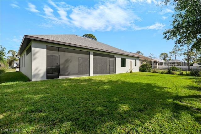 back of house with a yard, a sunroom, and stucco siding