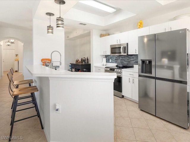 kitchen with arched walkways, light tile patterned floors, visible vents, appliances with stainless steel finishes, and a kitchen breakfast bar