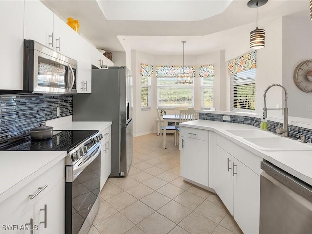 kitchen featuring tasteful backsplash, appliances with stainless steel finishes, light countertops, white cabinetry, and a sink