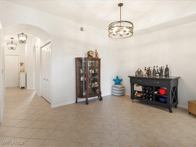 interior space featuring light tile patterned floors, visible vents, arched walkways, and a notable chandelier