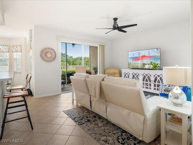 tiled living area with ceiling fan and baseboards