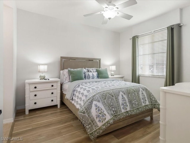 bedroom with ceiling fan, light wood-style flooring, and baseboards