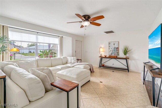 living area featuring visible vents, light tile patterned flooring, a ceiling fan, and baseboards