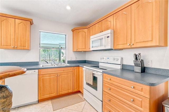 kitchen featuring light tile patterned floors, white appliances, dark countertops, and a sink