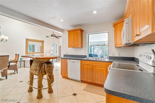 kitchen featuring light tile patterned floors, white appliances, dark countertops, and a sink