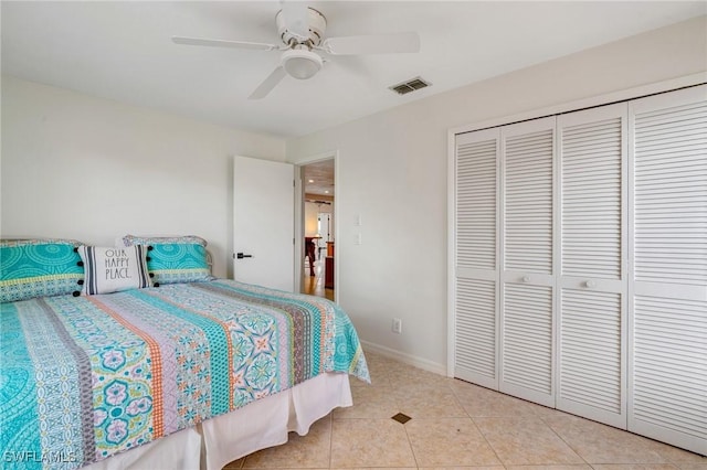 bedroom with a closet, visible vents, a ceiling fan, light tile patterned flooring, and baseboards