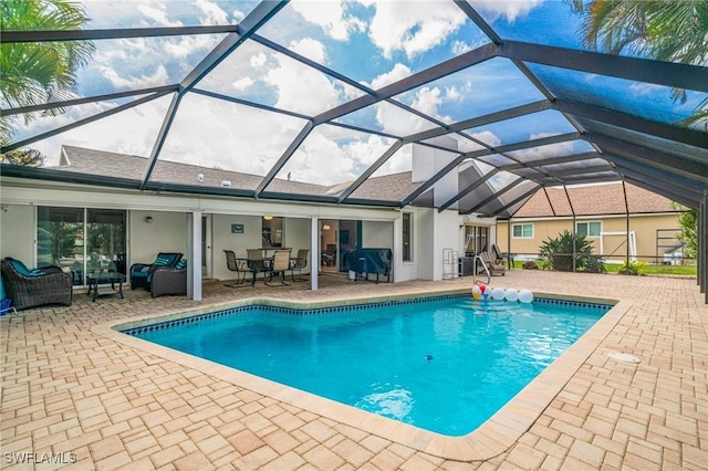 pool with glass enclosure, a patio area, and an outdoor hangout area