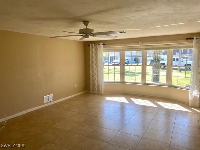 spare room with light tile patterned flooring, plenty of natural light, visible vents, and baseboards