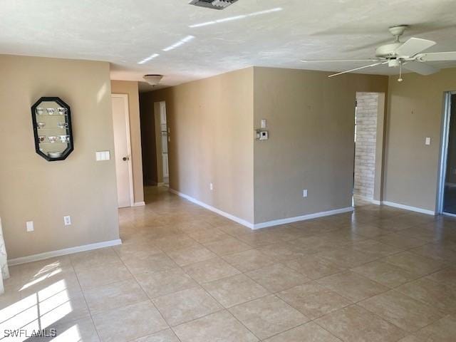 unfurnished room with light tile patterned flooring, ceiling fan, a textured ceiling, and baseboards