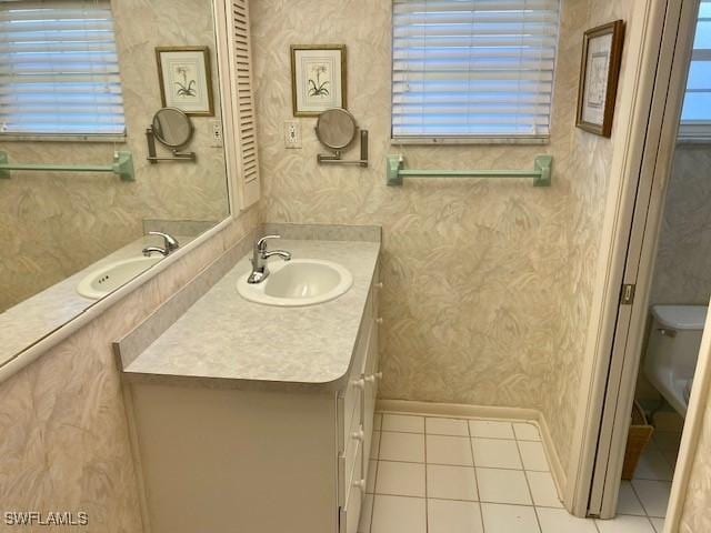 bathroom with toilet, tile patterned flooring, vanity, and wallpapered walls