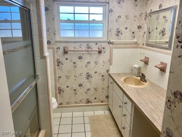 full bath featuring a wainscoted wall, an enclosed shower, vanity, and wallpapered walls