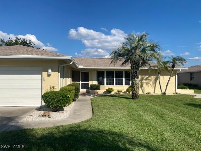 single story home with a front lawn, an attached garage, a shingled roof, and stucco siding