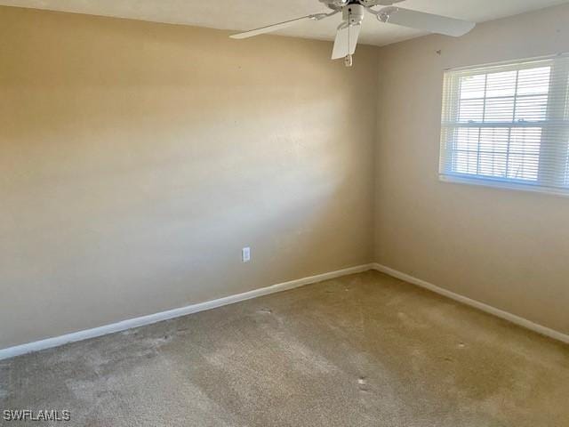 carpeted spare room with ceiling fan and baseboards