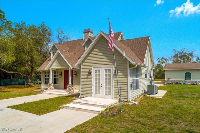 view of front of property featuring central AC unit, a shingled roof, french doors, a chimney, and a front yard