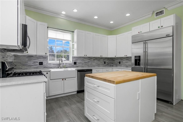 kitchen featuring butcher block countertops, appliances with stainless steel finishes, a sink, and ornamental molding