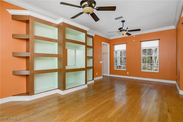 spare room featuring baseboards, wood-type flooring, visible vents, and crown molding