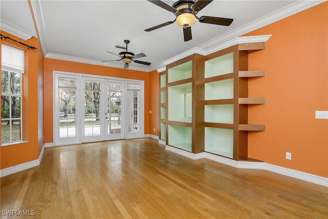 unfurnished living room featuring a wealth of natural light, baseboards, crown molding, and wood finished floors