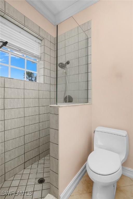 bathroom featuring tile patterned floors, crown molding, toilet, and a walk in shower