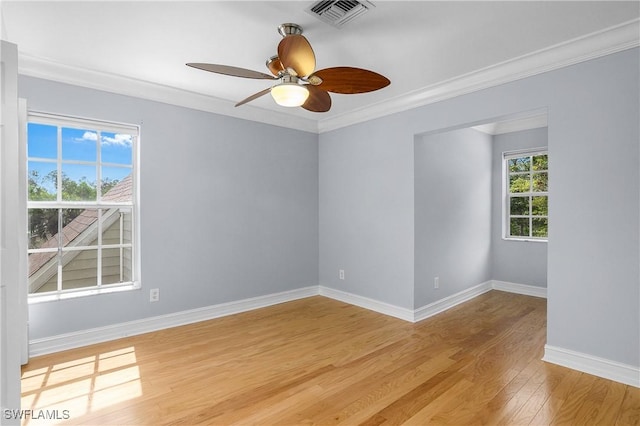 empty room featuring baseboards, visible vents, a ceiling fan, crown molding, and light wood-type flooring