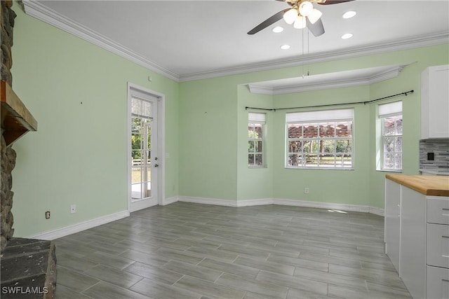 unfurnished living room featuring baseboards, a wealth of natural light, and crown molding