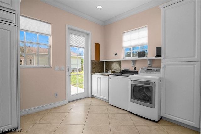 laundry room with crown molding, light tile patterned floors, cabinet space, and washer and dryer