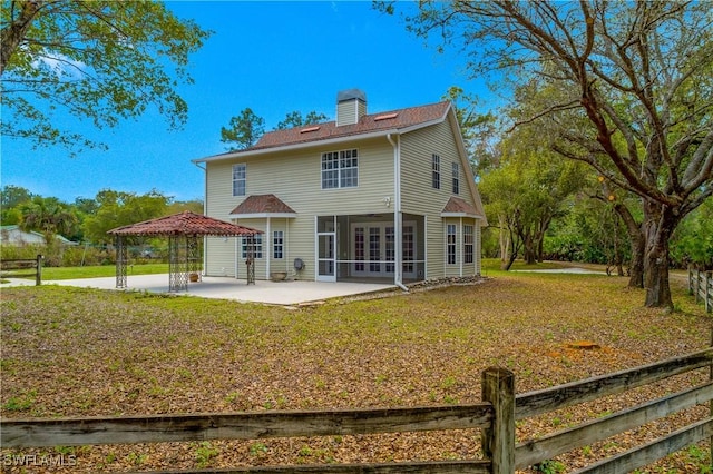 back of property featuring a sunroom, a chimney, a gazebo, a yard, and a patio area